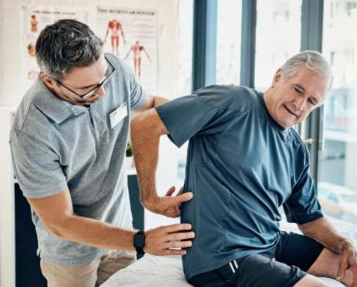 Elderly man having his back checked by a medical professional